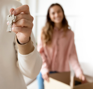 main tenant des clés et femme souriante en arriere plan