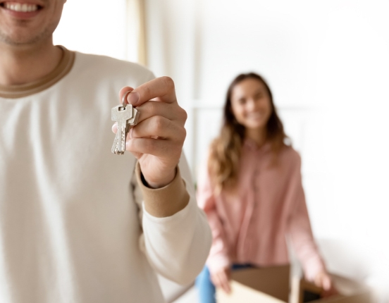 photo homme avec des clés dans la main et femme en arrière plan